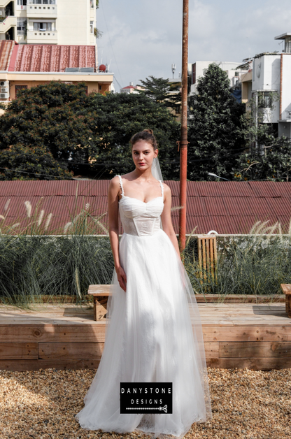 Bride in full corset lace dress with bustier bust and tulle overlay, full front view.