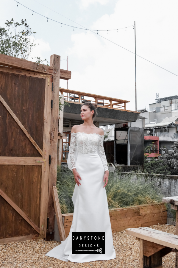 A full-length view of the model wearing the satin fishtail flat shoulder dress.