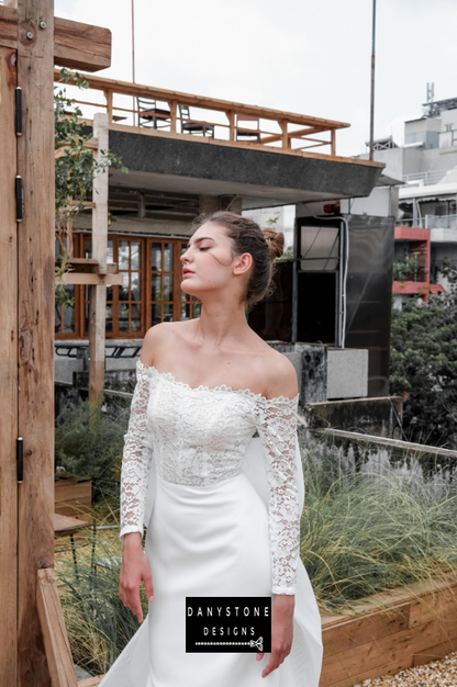 Model posing in an outdoor setting wearing the satin fishtail flat shoulder dress.