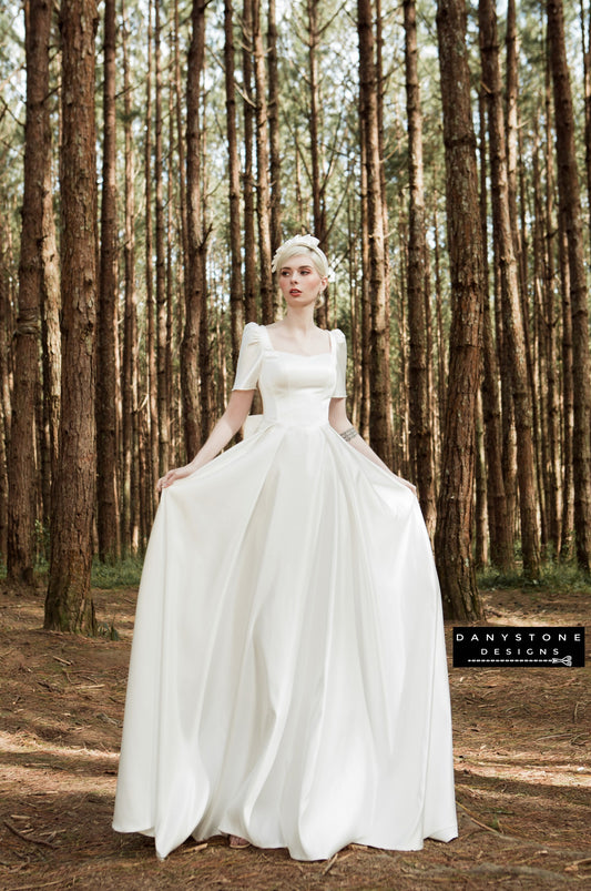 Elegant square-neck wedding dress with puff sleeves and full skirt in a forest setting – Danystone Designs