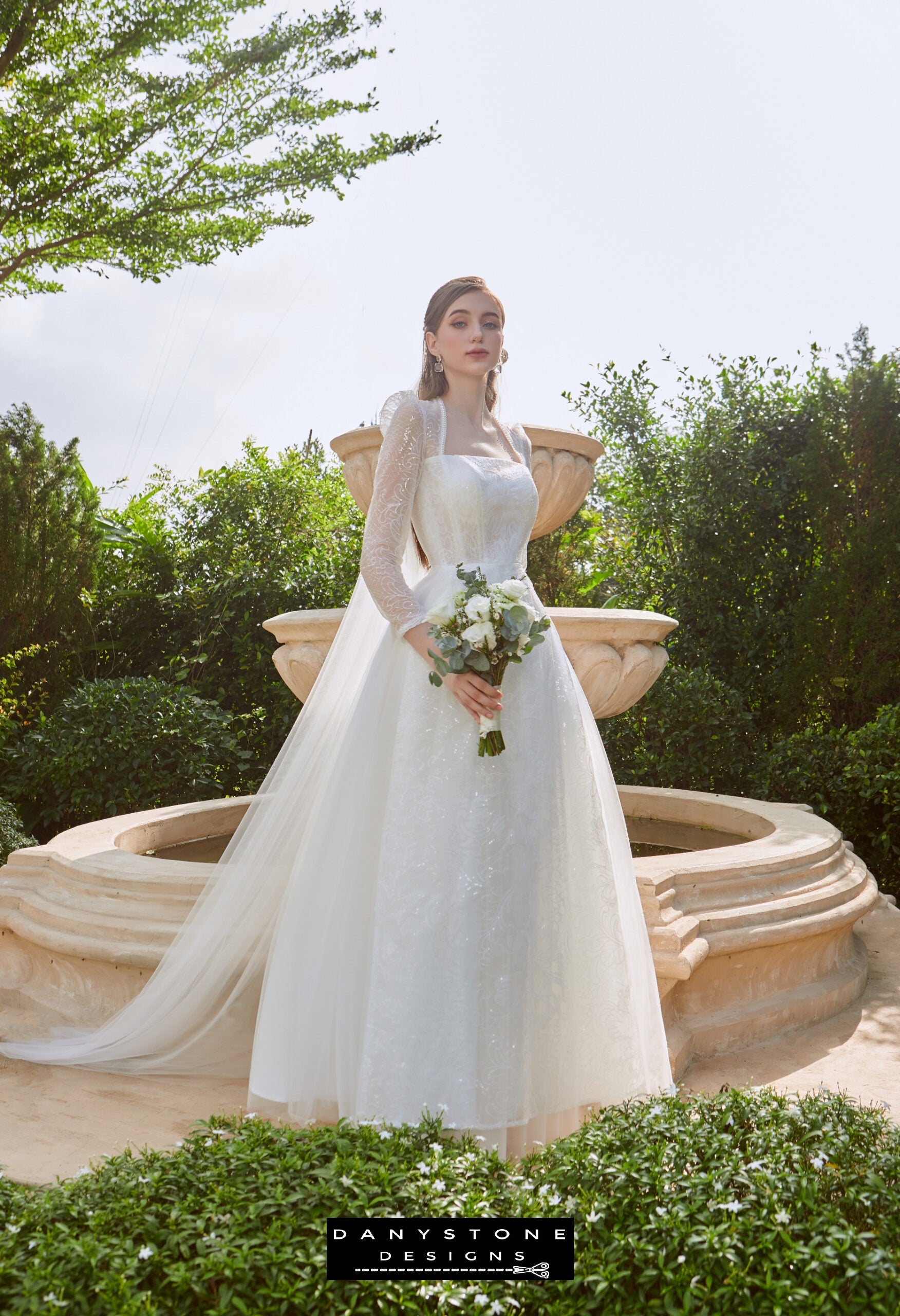 Cinderella Mesh Long Dress - Front View - Model showcasing the front view of the Cinderella mesh long dress with square neckline and sheer long sleeves, holding a bouquet.