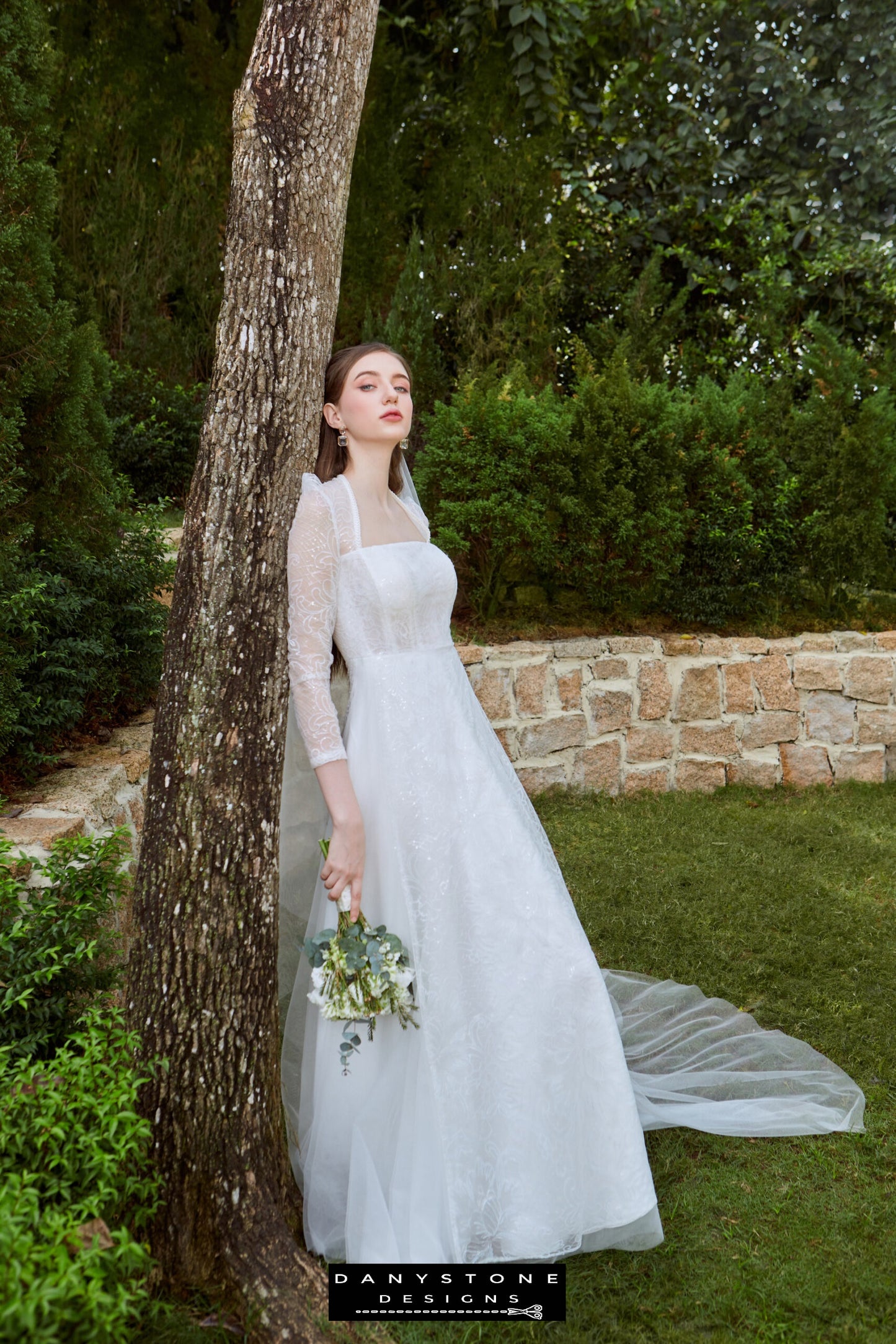 Elegant Bridal Gown with Sparkling Mesh Overlay - Side View - Model displaying the side view of the dress, highlighting the square neckline, lace detailing, and flowing A-line silhouette.