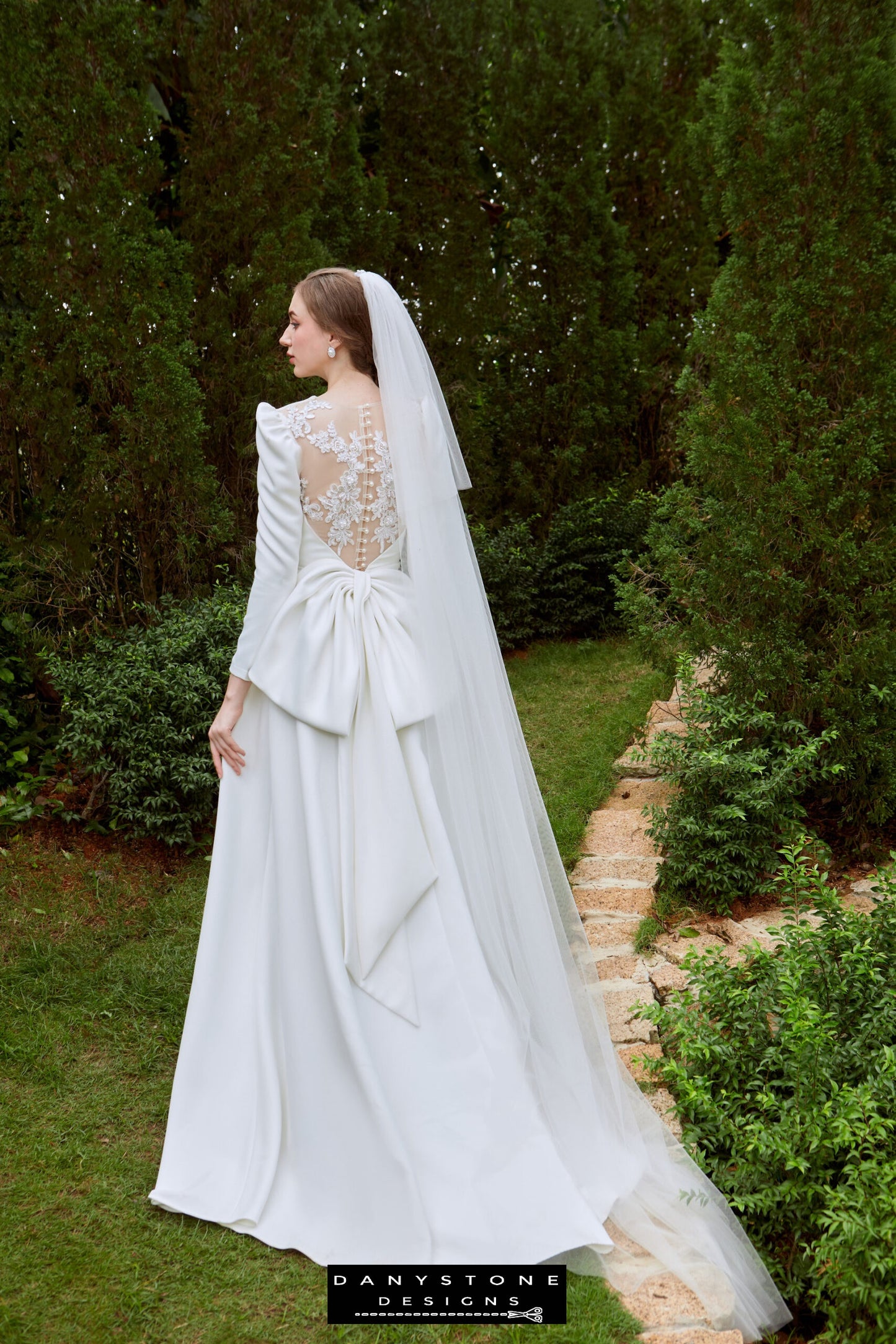 Sophisticated Bridal Gown with Embroidered Back - Model posing in the Snow White Queen Neck Satin dress, showcasing the intricate floral embroidery and large satin bow at the back.