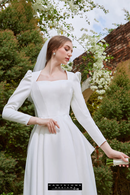 Elegant Bridal Gown with Large Bow - Full View - Model displaying the full view of the dress, highlighting the Queen neckline, long sleeves, and A-line silhouette.