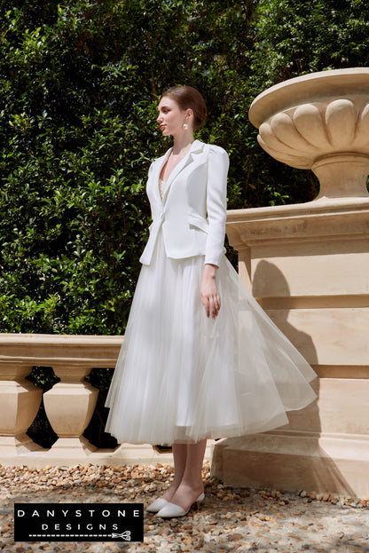 Bride in strapless wedding dress with satin vest, standing beside classical statues.