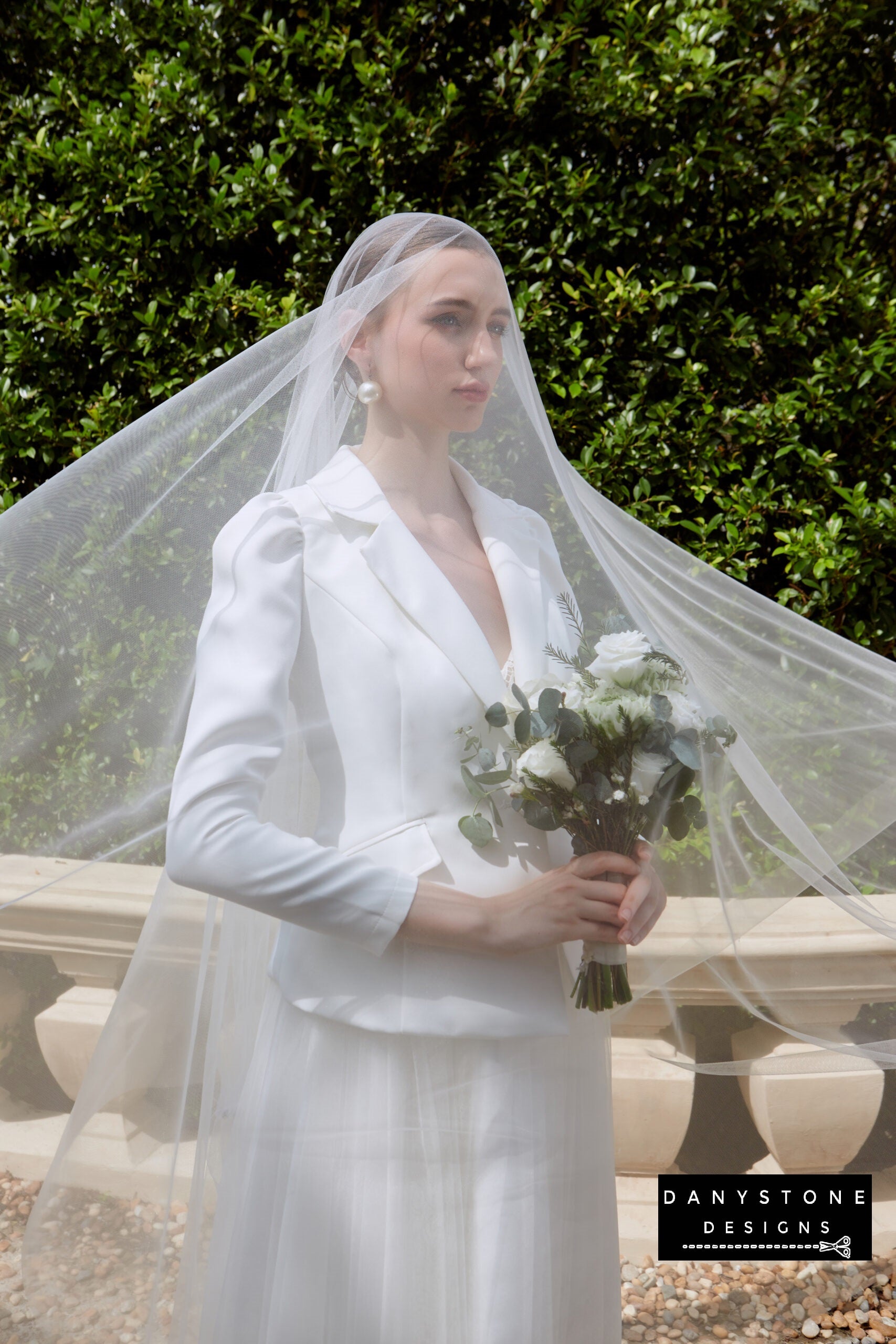 Bride in strapless wedding dress with satin vest and veil, holding a bouquet.