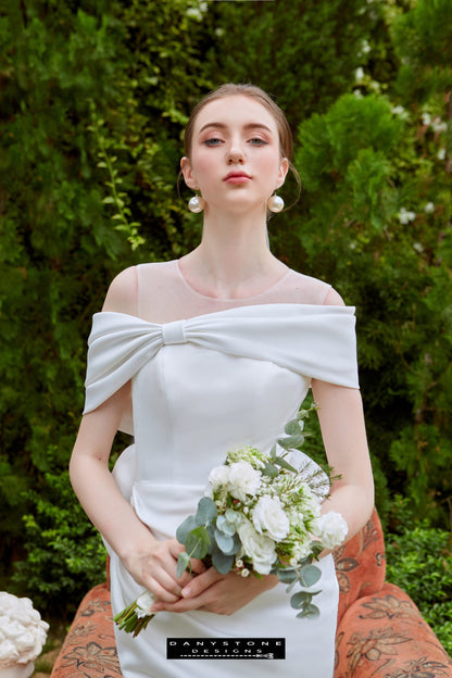 Mini Dress with Off-Shoulder Design - Front View - Model posing in the front view of the mini dress with flat shoulders and a bouquet.