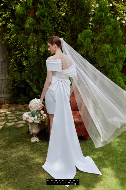 Mini Dress with Flat Shoulders and Bow Back - Back View - Model showcasing the back view of the mini dress with flat shoulders and a bow detail, holding a bouquet.