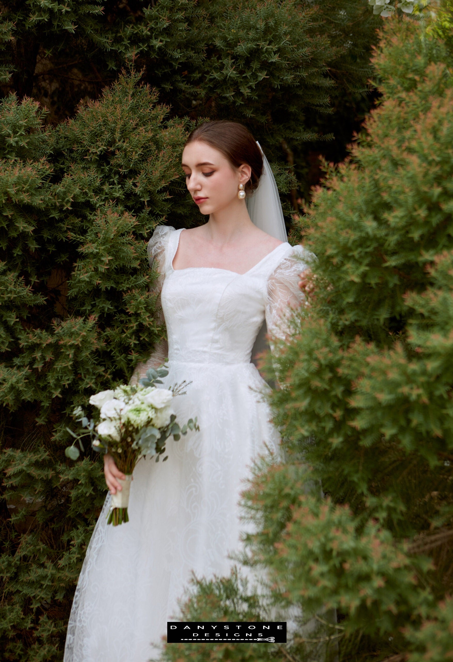 Cinderella Long Sleeve Square Neck Bridal Gown - Garden Setting - Model walking in a garden setting wearing the Cinderella long sleeve square neck bridal gown with lace fabric.