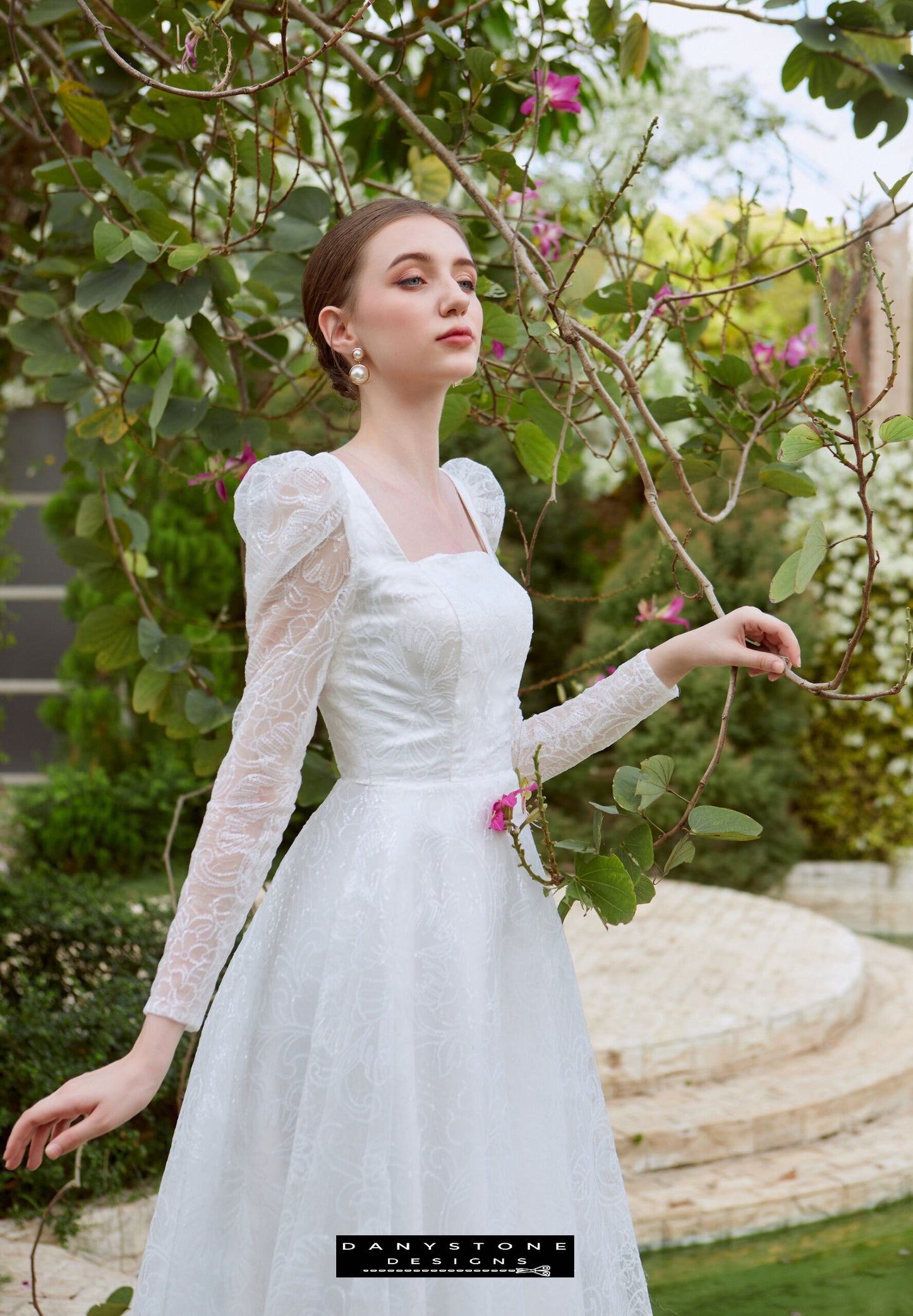 Cinderella Long Sleeve Square Neck Dress - Elegant Pose - Model posing elegantly in the Cinderella long sleeve square neck dress, surrounded by beautiful garden flowers.