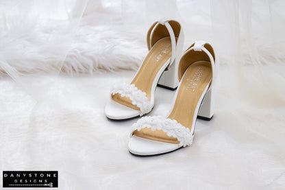 Top view of matte white leather heels with white rose lace trim, showcasing elegant design.