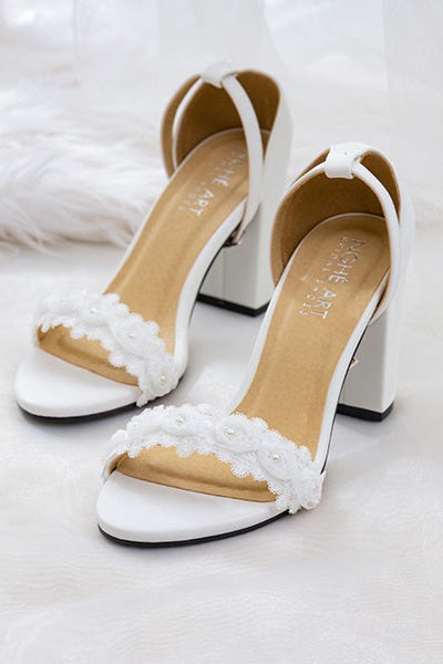 Top view of matte white leather heels with white rose lace trim, showcasing elegant design.