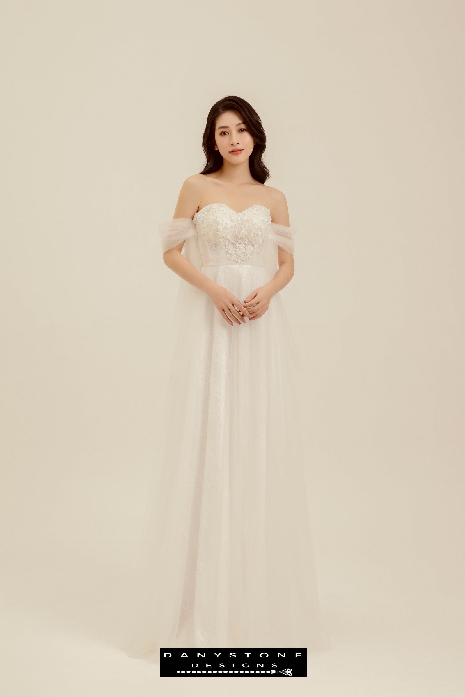 Romantic Off-the-Shoulder Lace Wedding Dress - Model standing gracefully, presenting the full view of the A-line silhouette and delicate lace details.