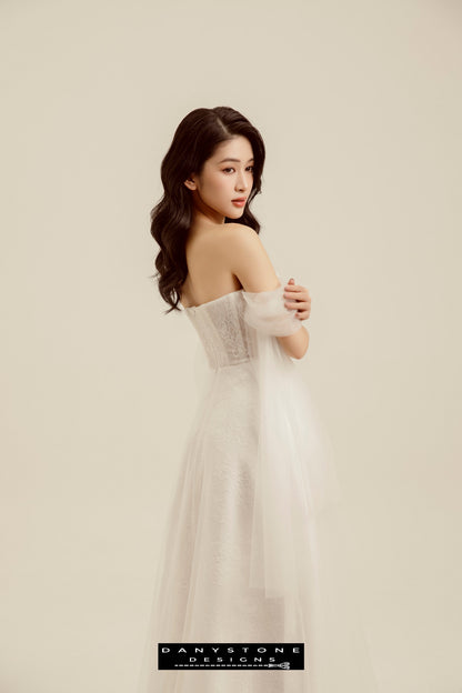 Ethereal Bridal Gown with Lace and Tulle Sleeves - Model posing to the side, showcasing the soft tulle sleeves and flowing lace fabric of the gown.