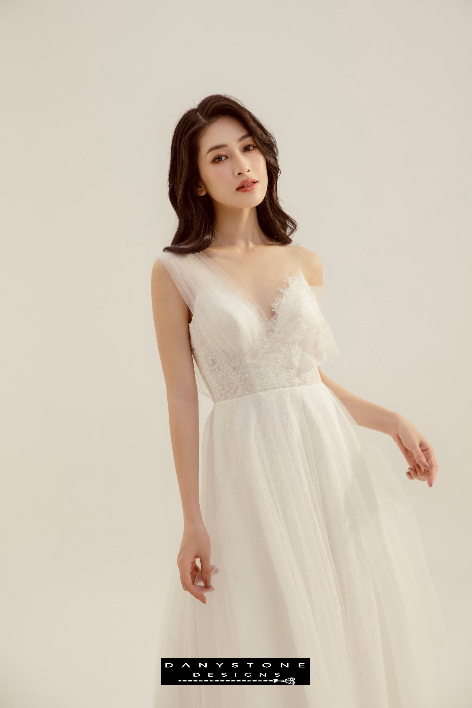 Model displaying the elegant asymmetrical one-shoulder design of the wedding dress.