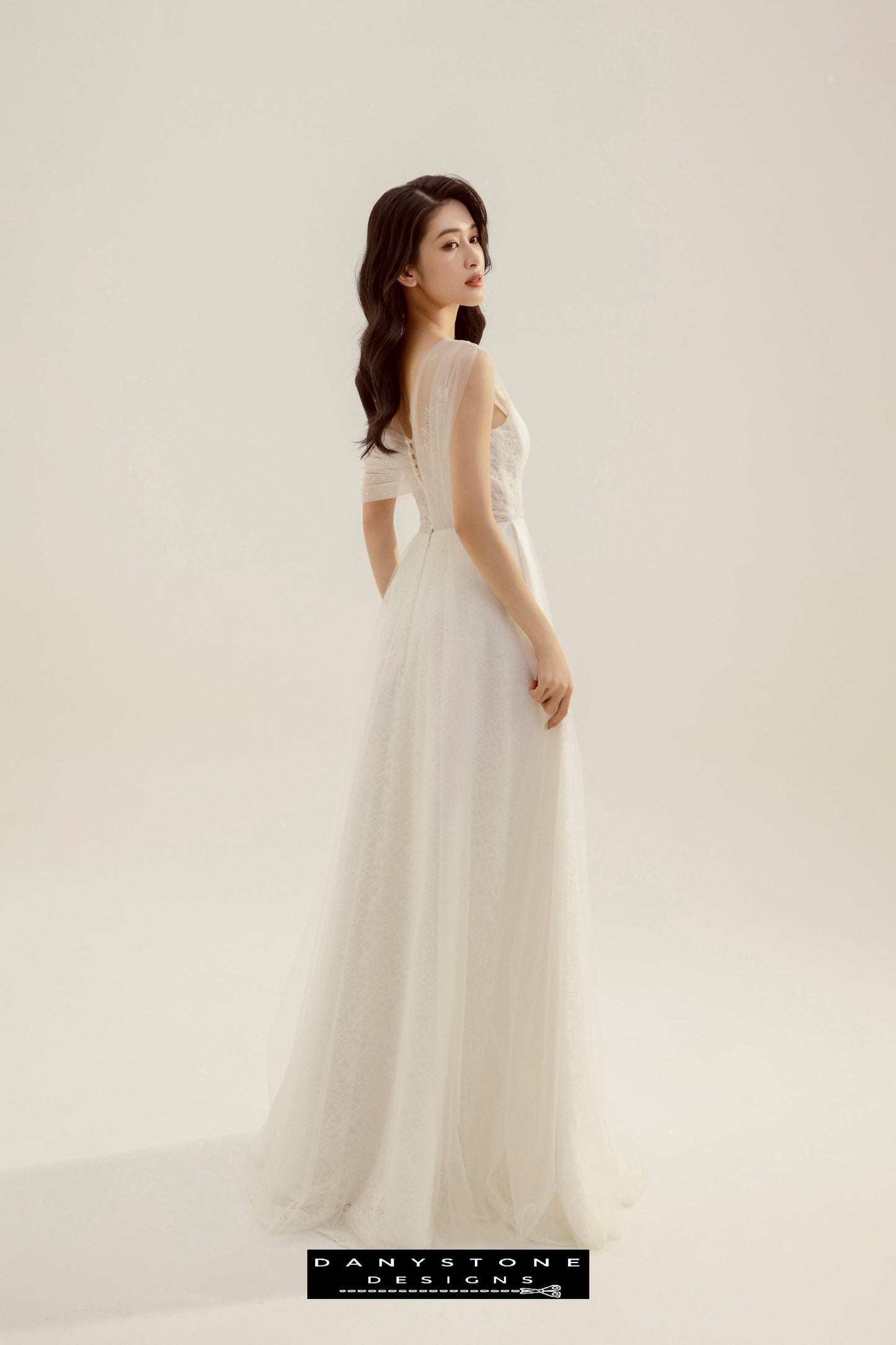 Model showing the back button closure and flowing skirt of the Beaded Floral Lace Pleated Wedding Dress.