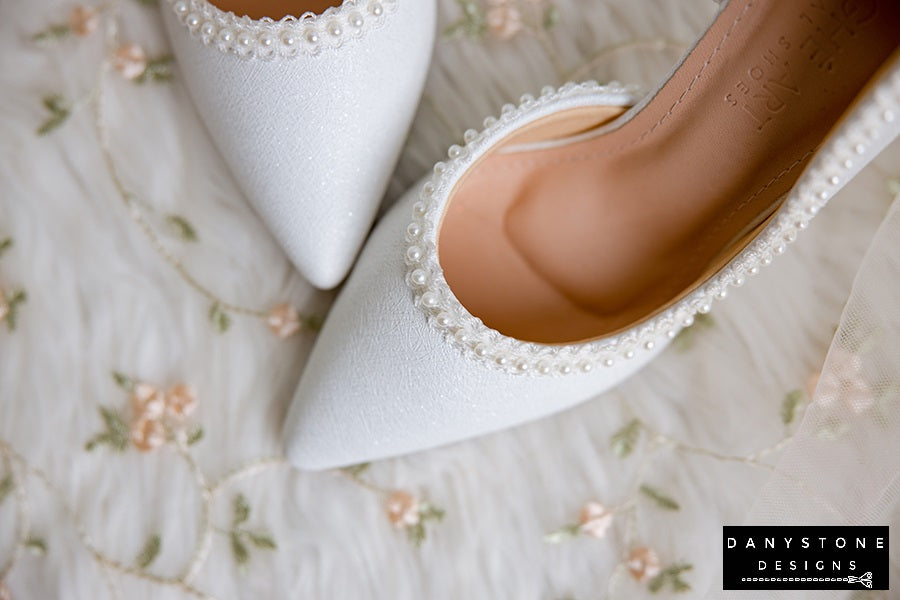 Pair of wedding shoes with pearl trim, showcasing metallic scratched leather and elegant design.