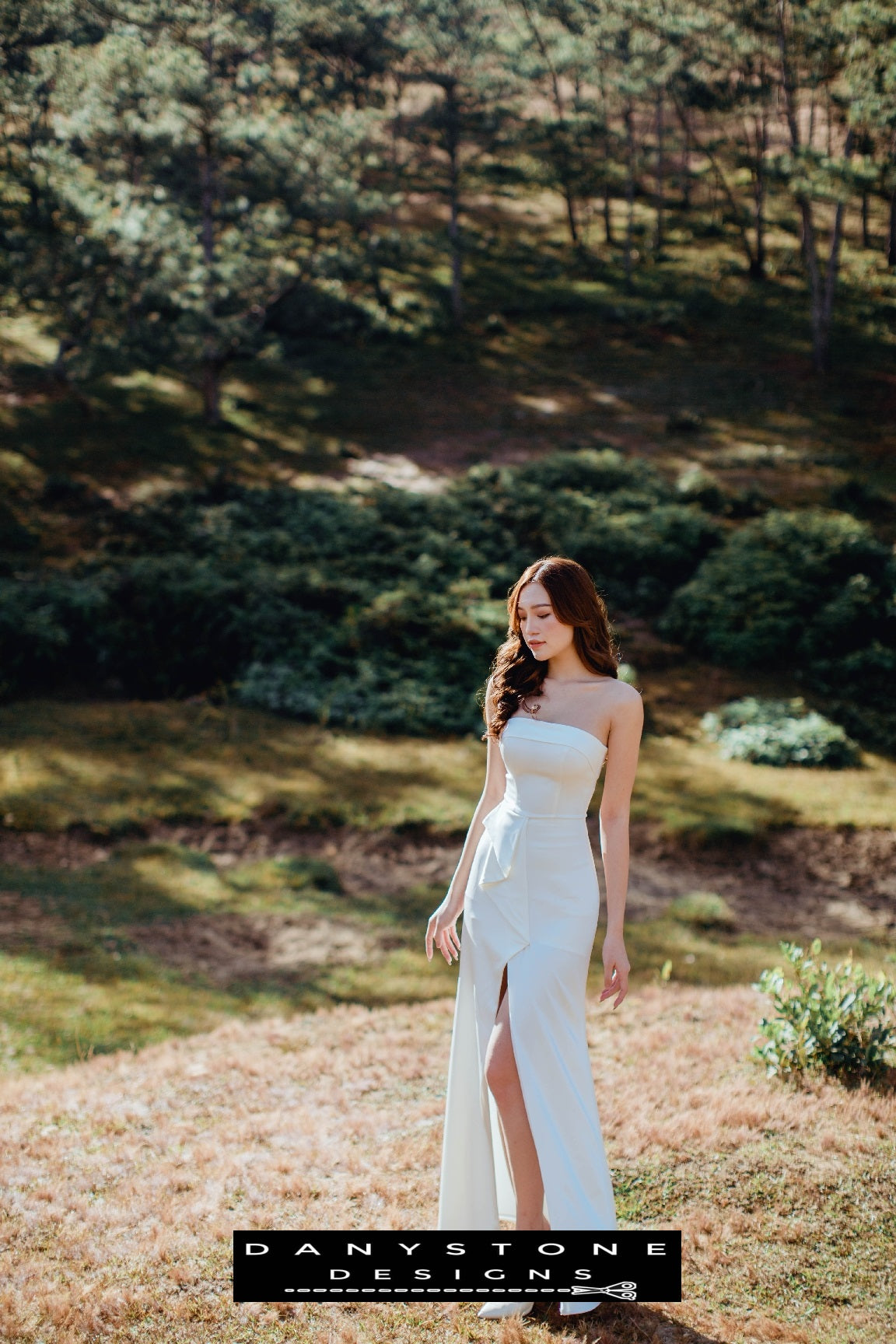 Bride wearing a modern strapless wedding gown with bow detail and front slit – Danystone Designs