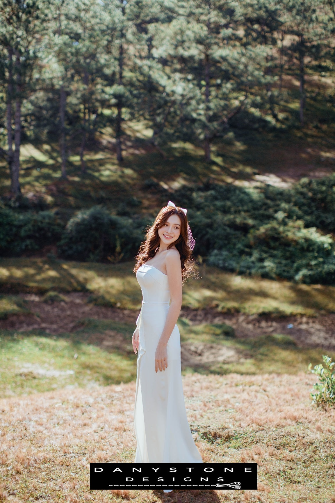 Beautiful bride in a strapless wedding dress with bow detail and front slit, perfect for modern weddings – Danystone Designs