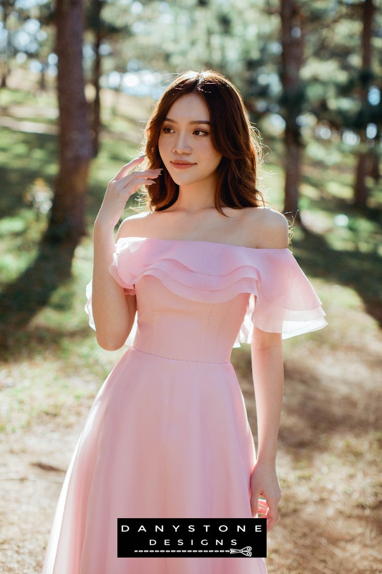 Elegant pink silk chiffon dress with off-the-shoulder ruffles model posing outdoors