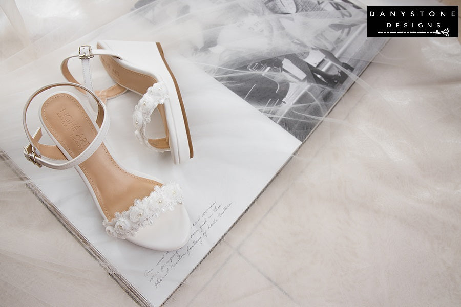 Top view of matte white leather canoe heels with white rose lace trim, highlighting the delicate floral design.