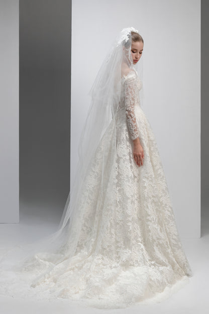 White lace wedding dress with a long veil on a plain background