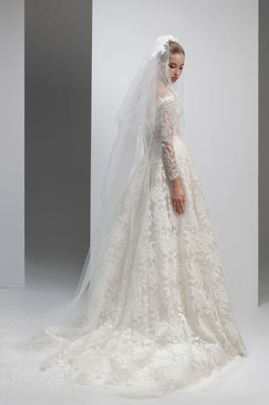 White lace wedding dress with a long veil on a plain background
