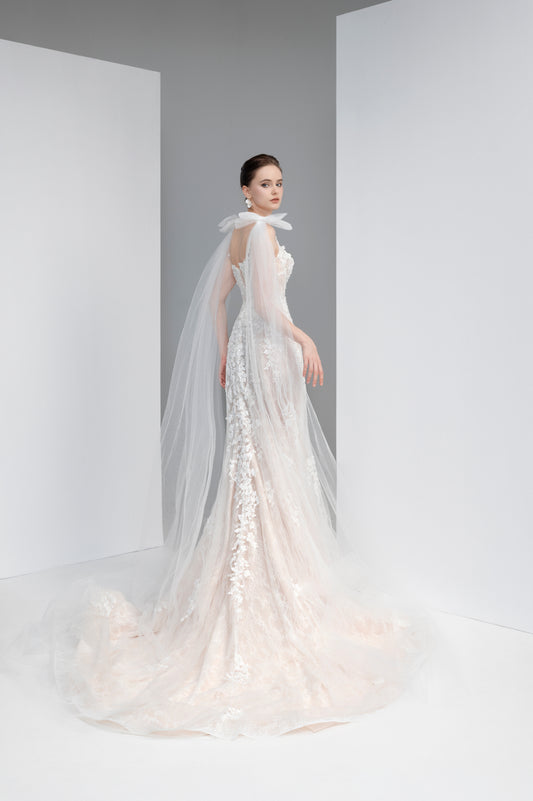 Woman wearing a white wedding dress with a long train in a minimalistic setting