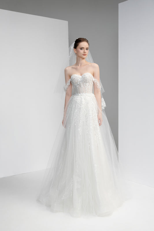 Model wearing a white wedding dress with lace detailing against a neutral background