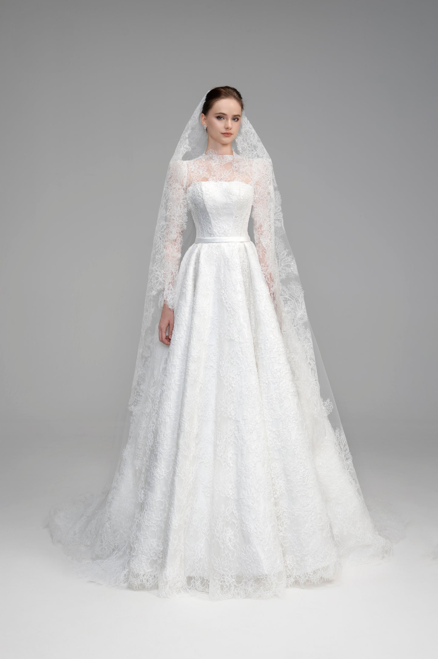 White wedding dress with a long veil on a gray background