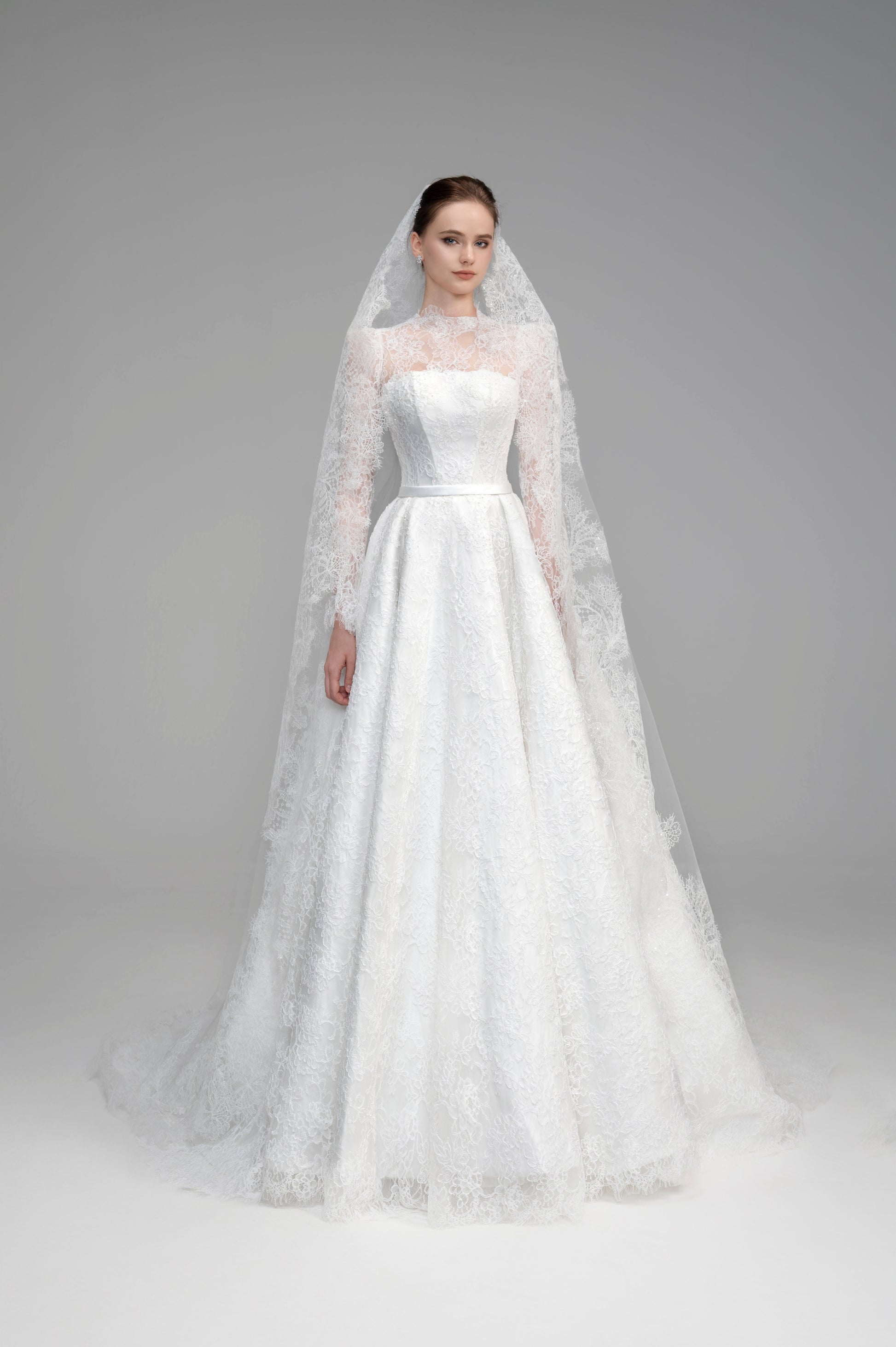 White wedding dress with a long veil on a gray background