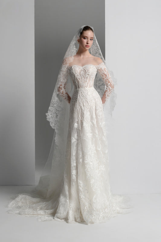 Woman wearing a white lace wedding dress with a matching veil against a plain background