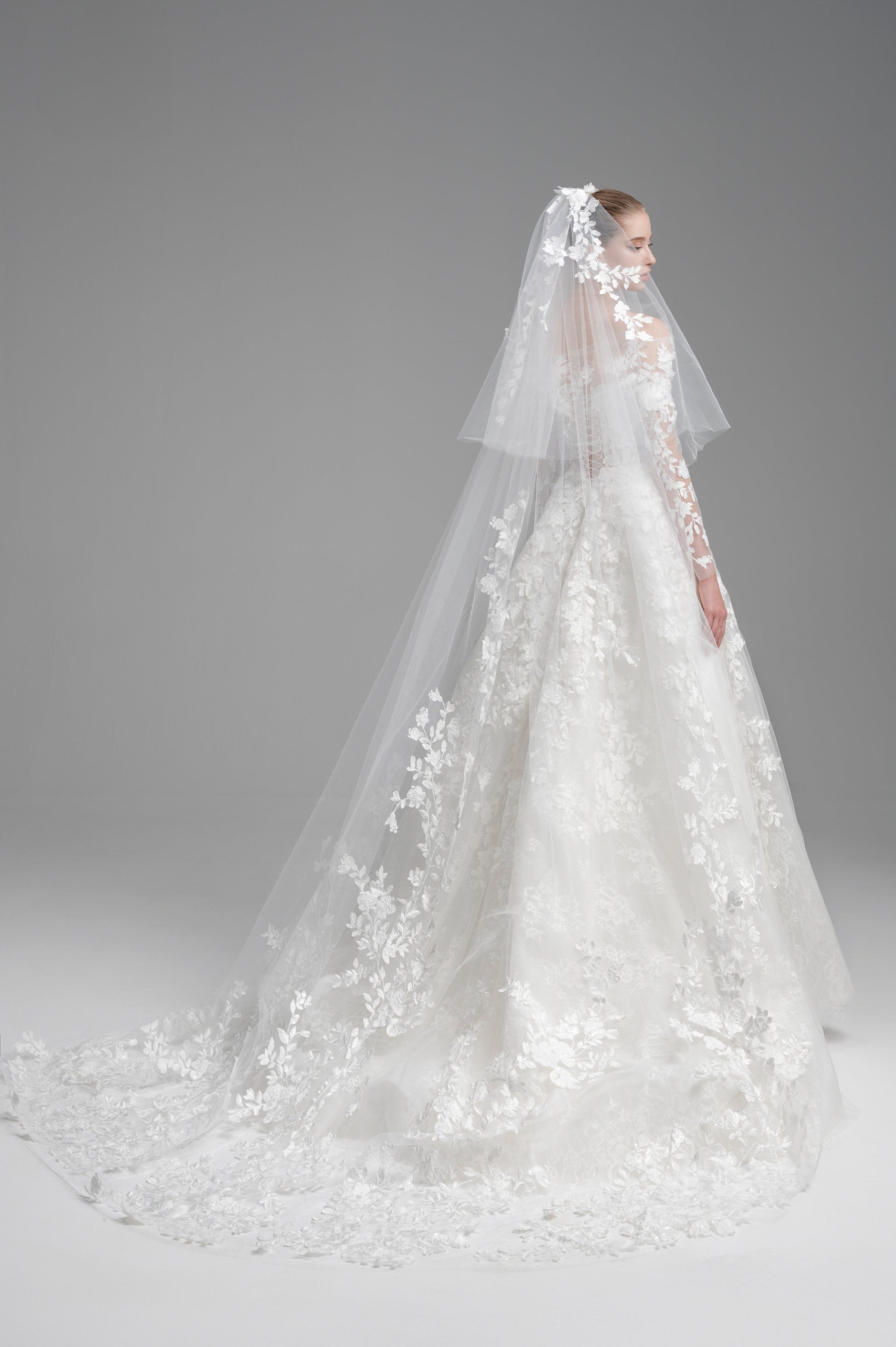 Elegant white wedding dress with a long veil on a gray background