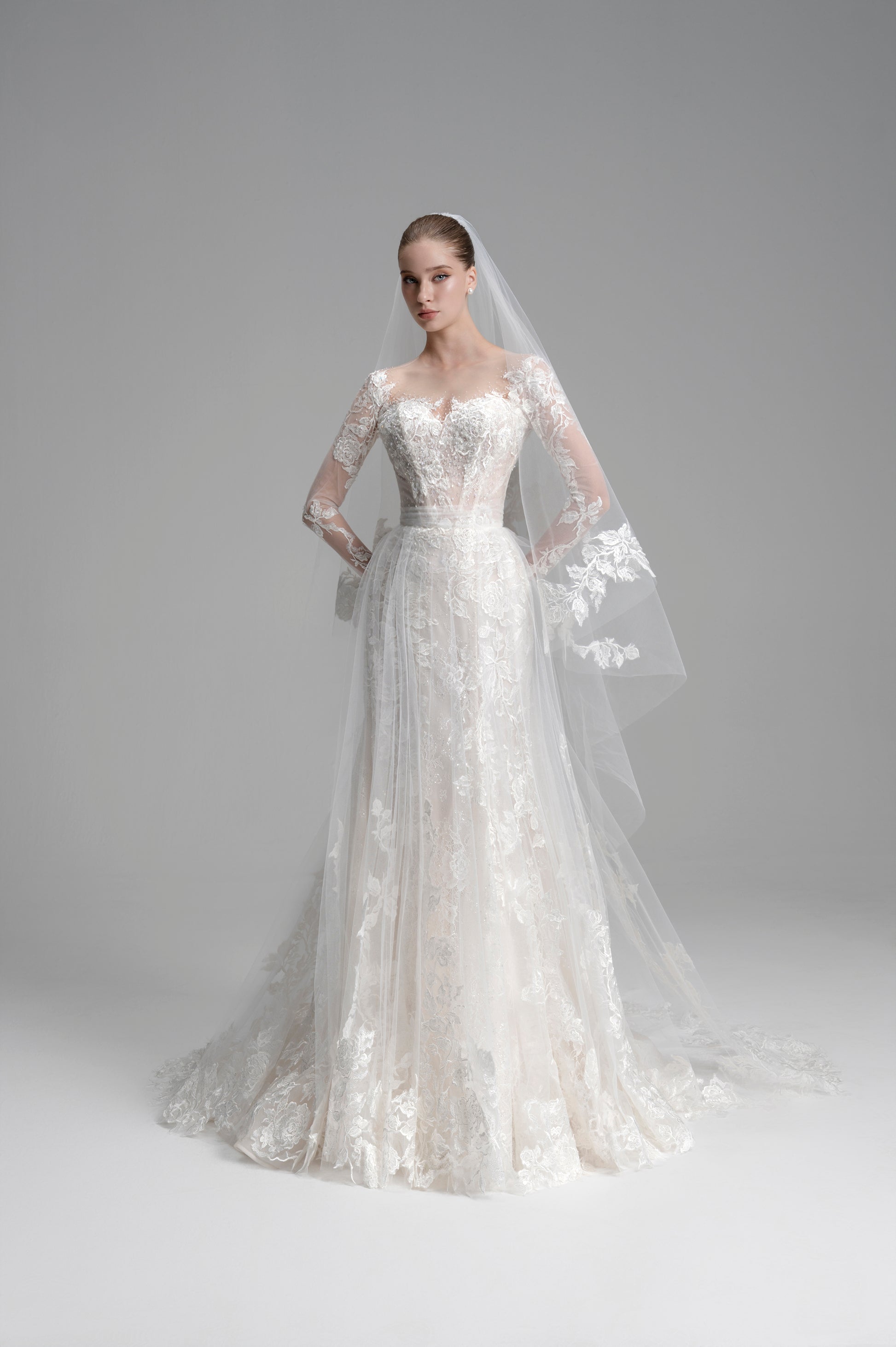 White wedding dress with long sleeves and a veil on a gray background