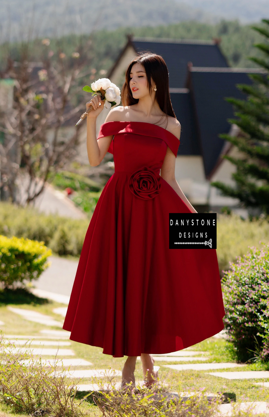 "Model in elegant red off-shoulder dress holding flowers"