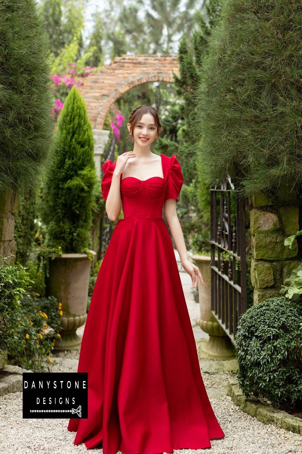 Elegant Red Wedding Dress with Pleated Details in Front of Greenery