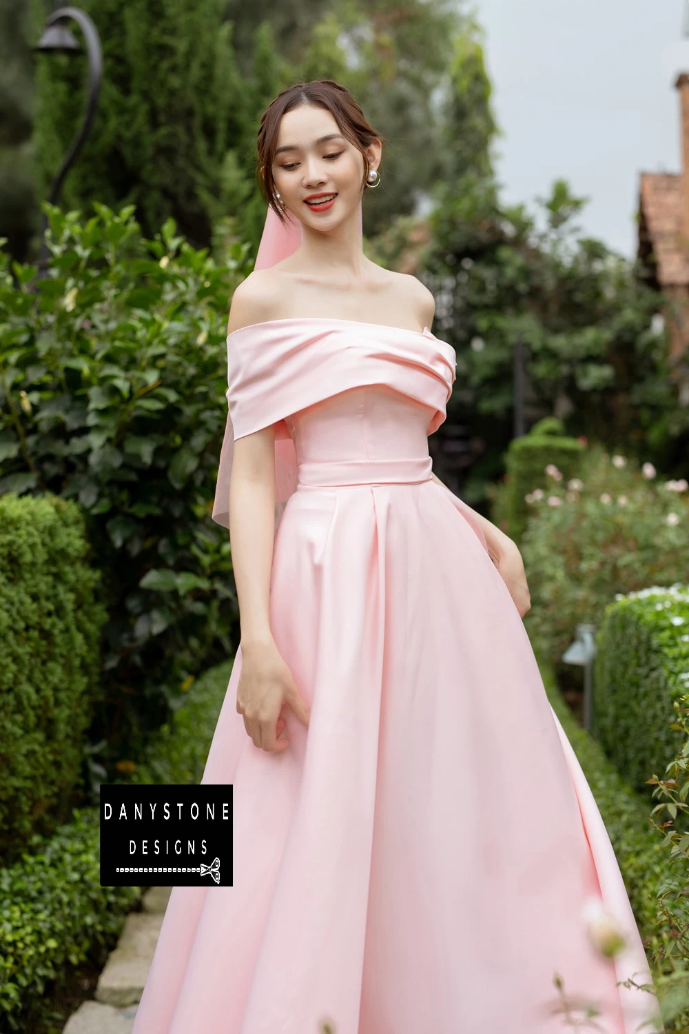 Bride in Elegant Pink Off-the-Shoulder Wedding Dress with Cross-Waist Design in Garden Setting