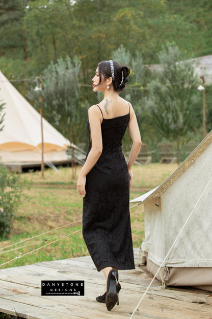 Sophisticated woman in a black lace dress with slit and wrapped buttons standing outdoors