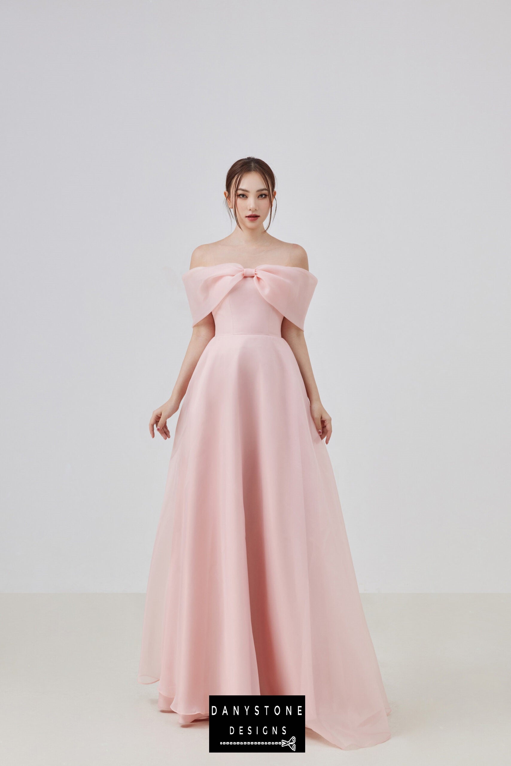 Model wearing an elegant pink off-shoulder silk chiffon dress with a bow