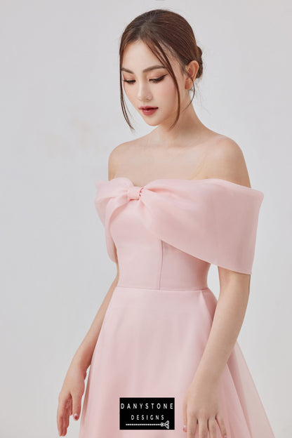 Pink off-shoulder silk chiffon dress with bow detail modeled indoors