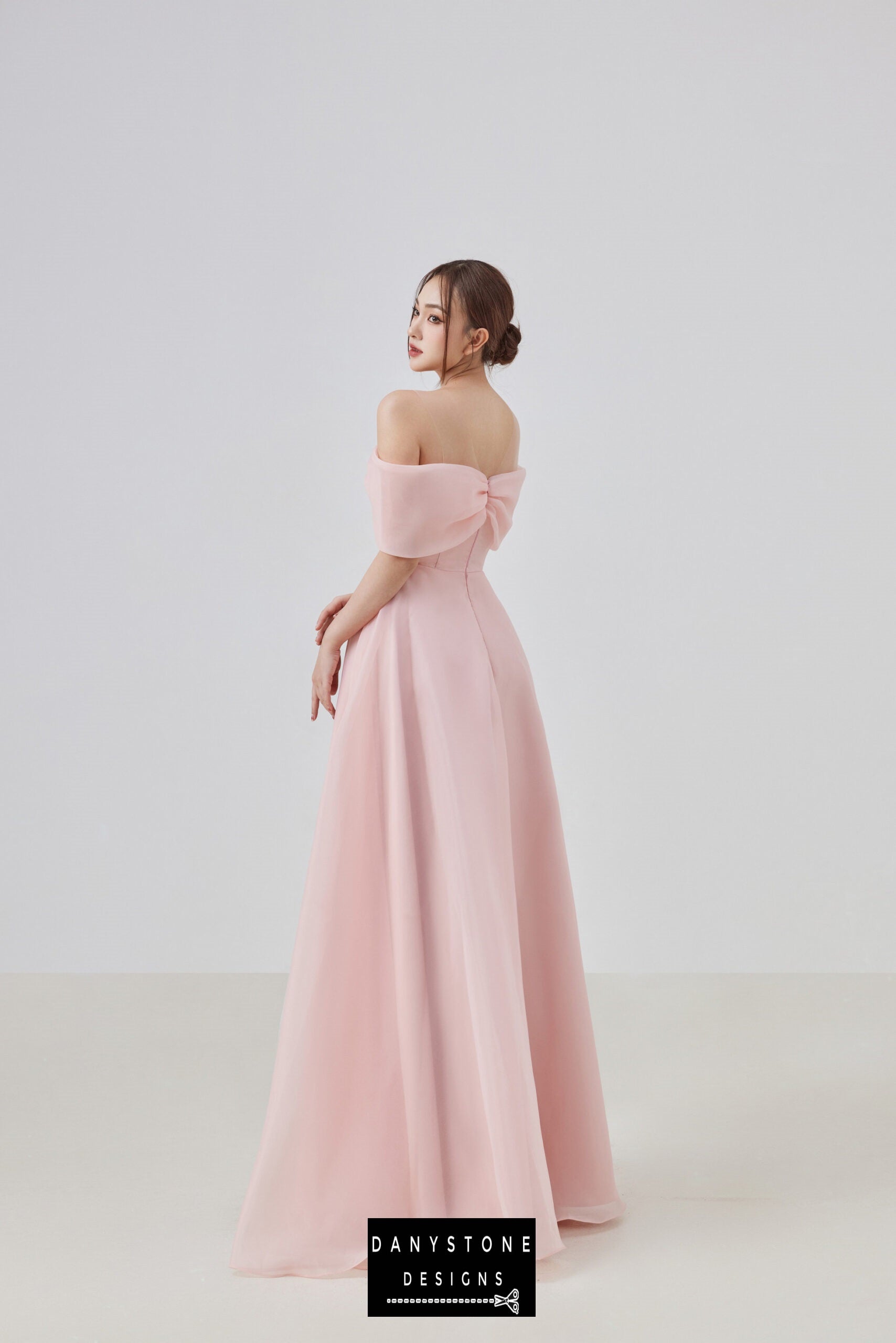 Elegant pink off-shoulder dress with a bow at the chest worn by a model