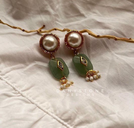 Jade stone drop earrings with pearl stud, featuring green jade stones, gold-toned accents, and tiny pearl dangles, displayed on a soft white fabric background.