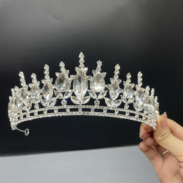 Hand holding a Regal Crystal Bridal Crown with sparkling crystals in a majestic design.