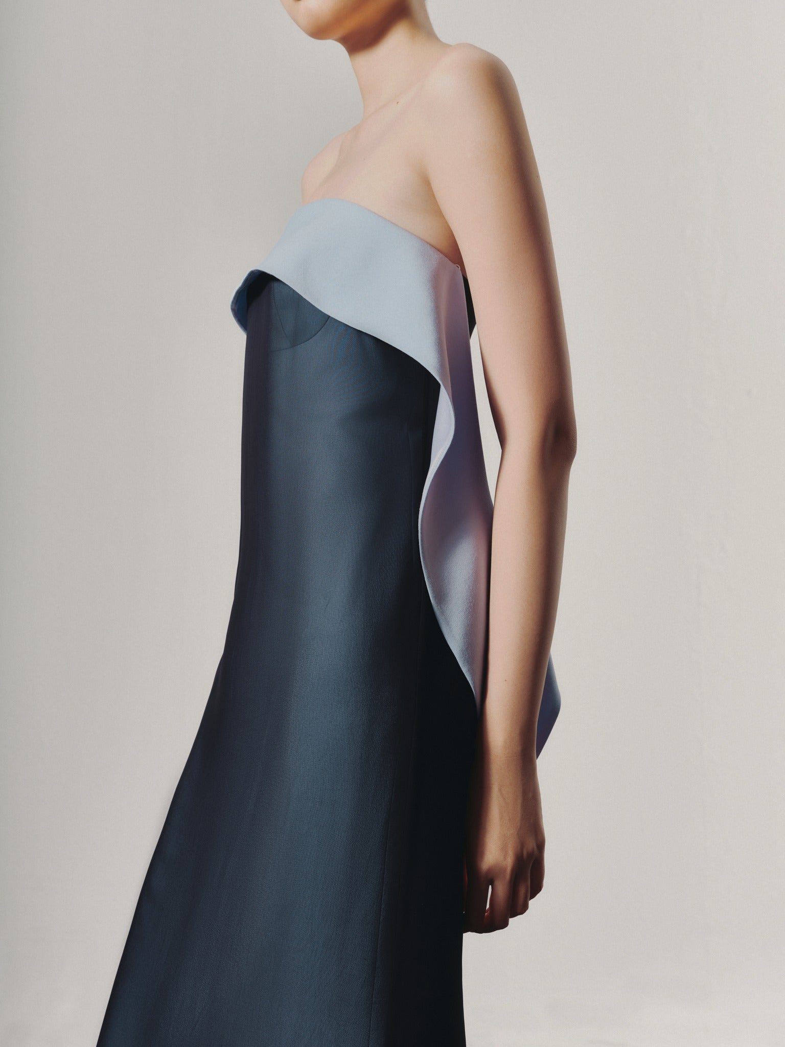 Woman wearing a strapless dress with a gradient design on a plain background