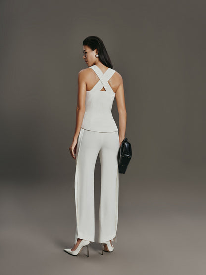 Woman wearing a white outfit with a criss-cross back design on a gray background
