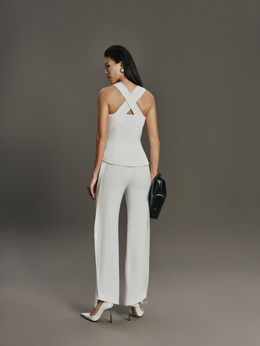 Woman wearing a white outfit with a criss-cross back design on a gray background