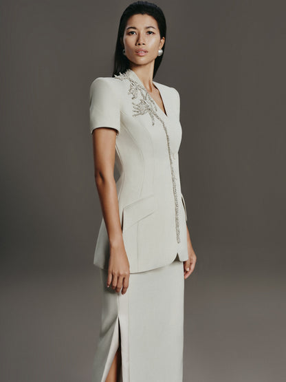 Woman wearing a white dress with embroidery on a gray background