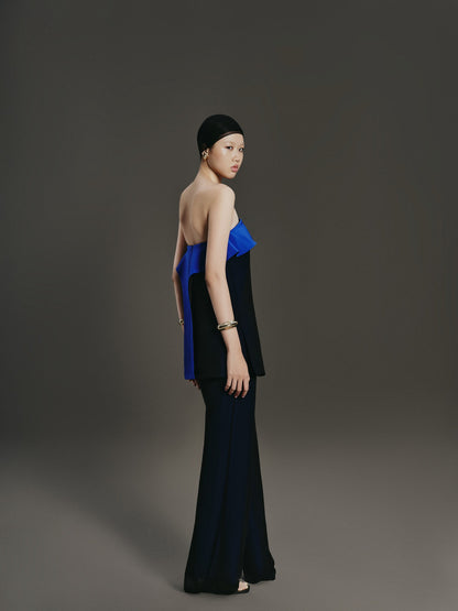 Woman wearing a black and blue strapless dress against a gray background