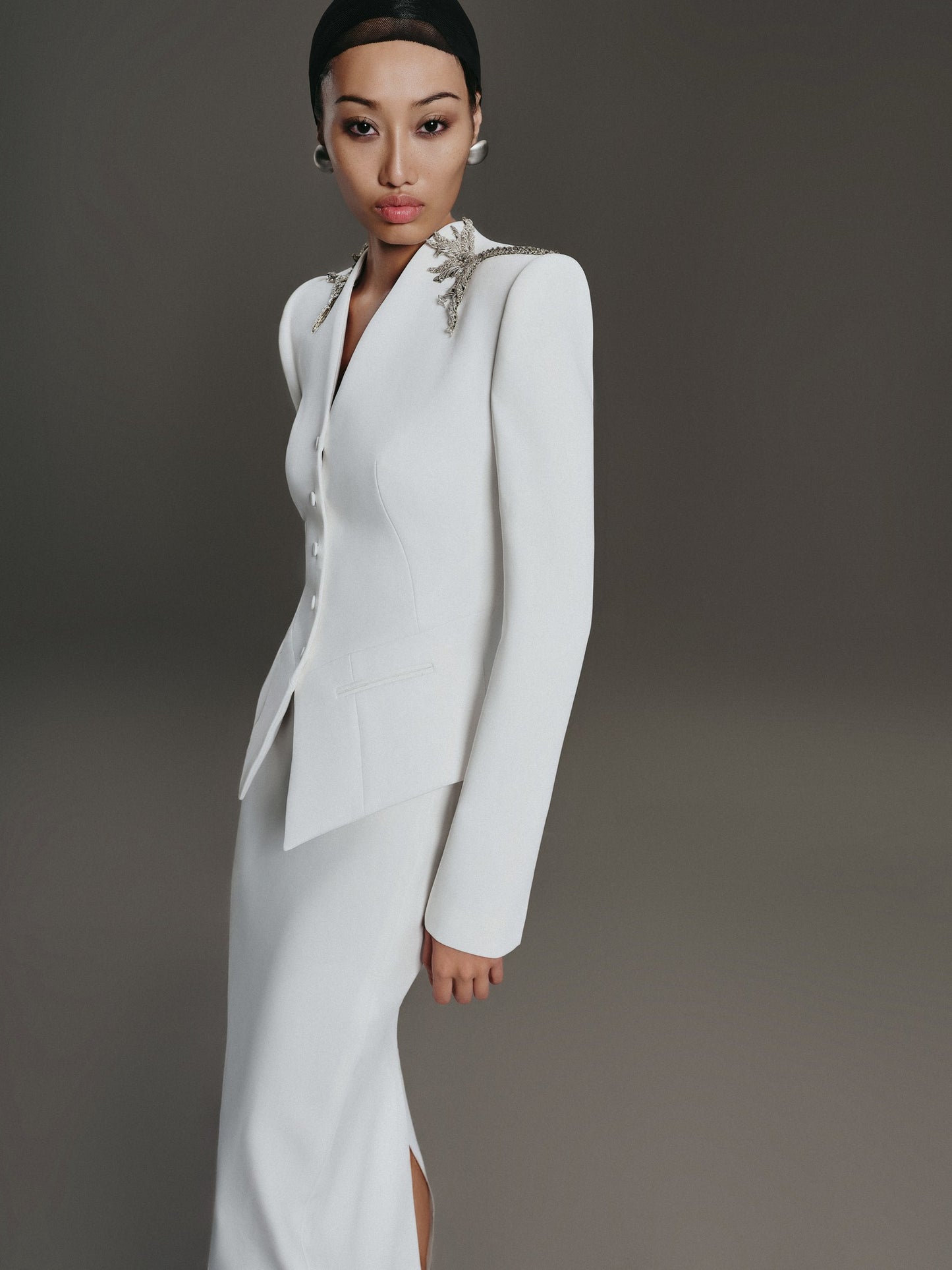 Woman wearing a white bridal suit with a gray background