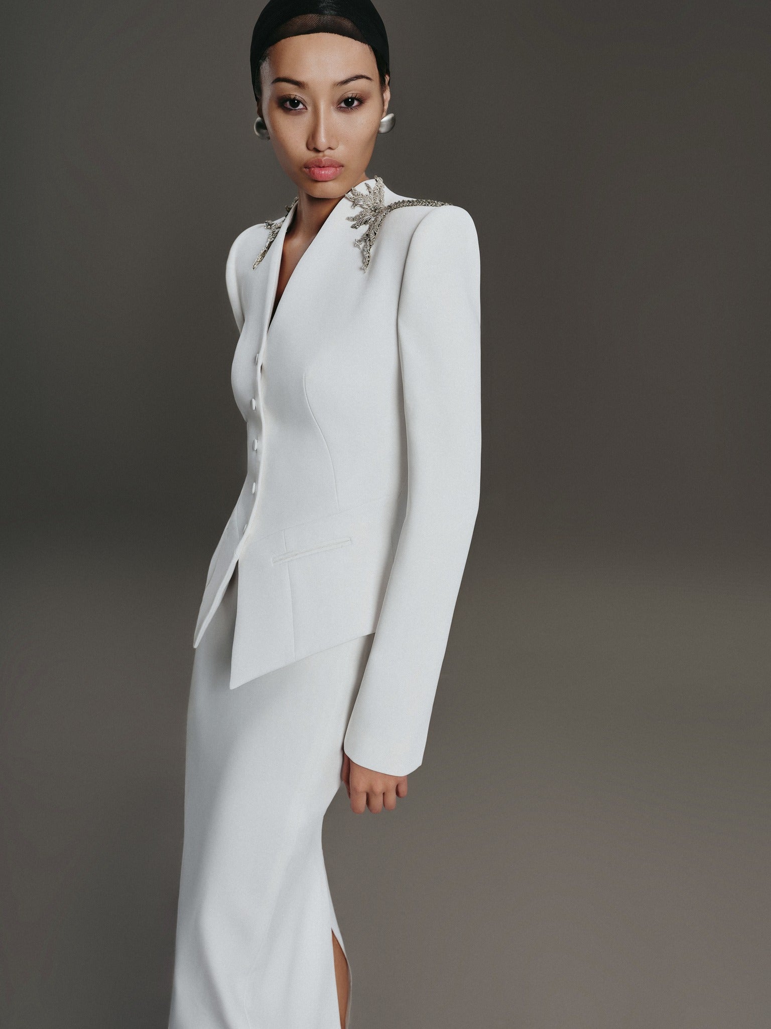 Woman wearing a white bridal suit with a gray background